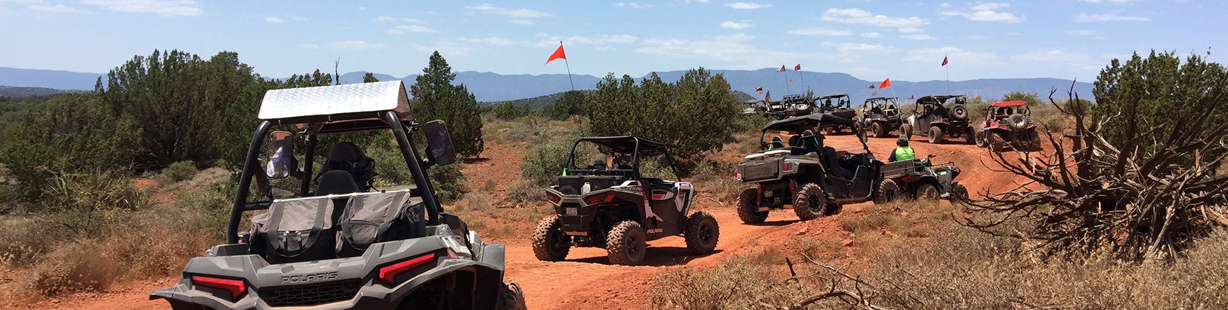 A large group of off highway vehicles explore a red dirt trail in the Sedona area