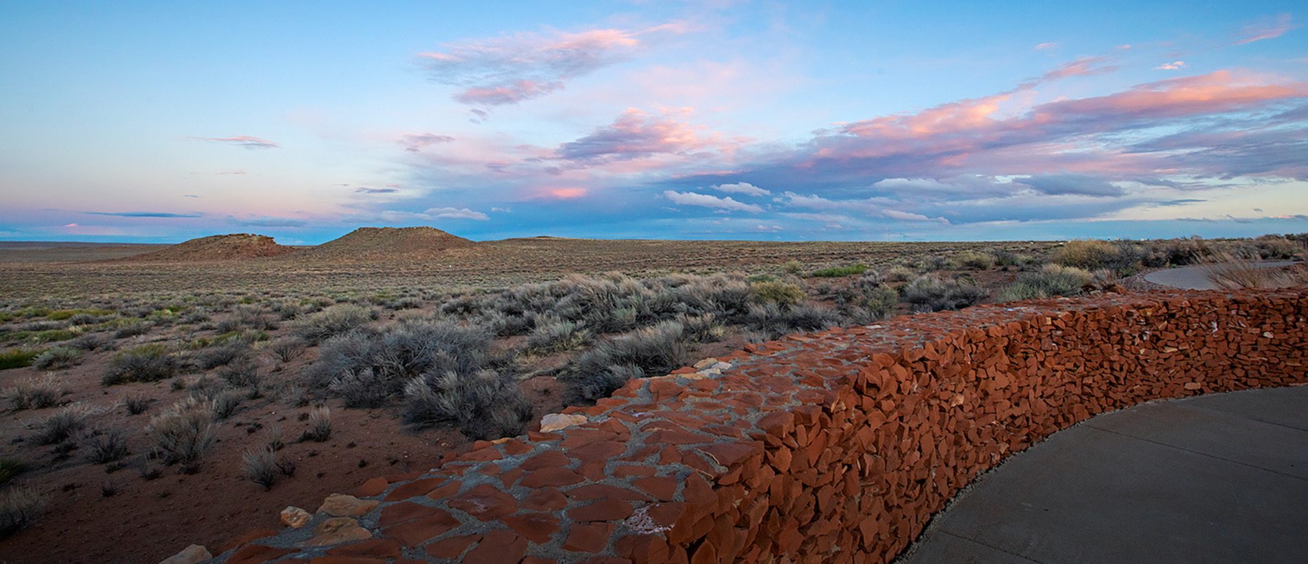 The sun sets behind a rock wall at Homolovi State Park