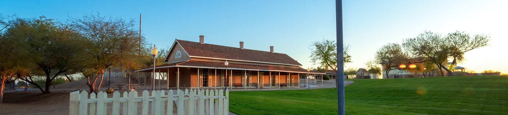 The main park building is seen in the distance on the far end of a field of green grass.