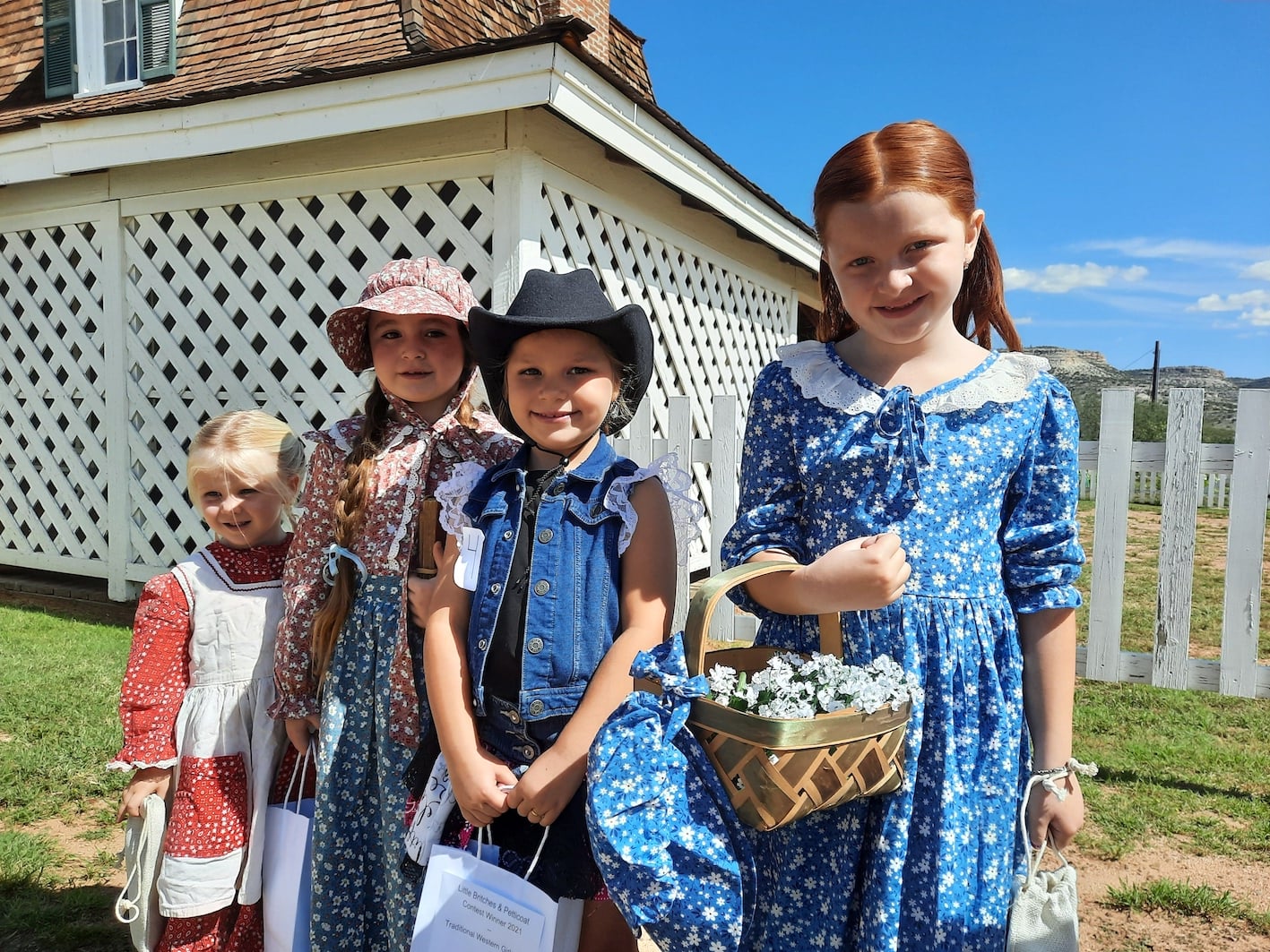 Four children dressed in period clothes in front of the fort