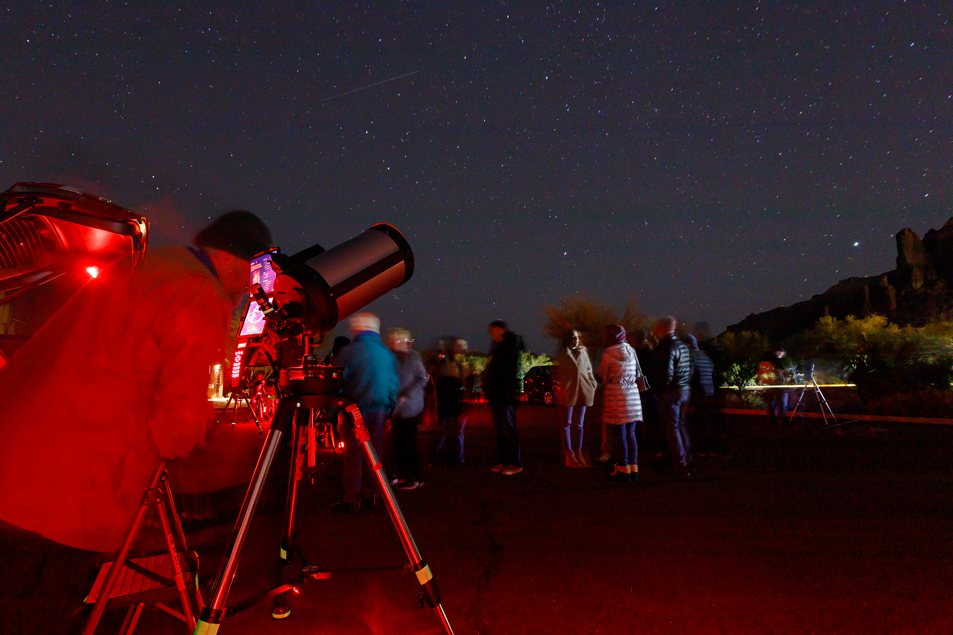 Visitors look through telescopes under a starry night sky.